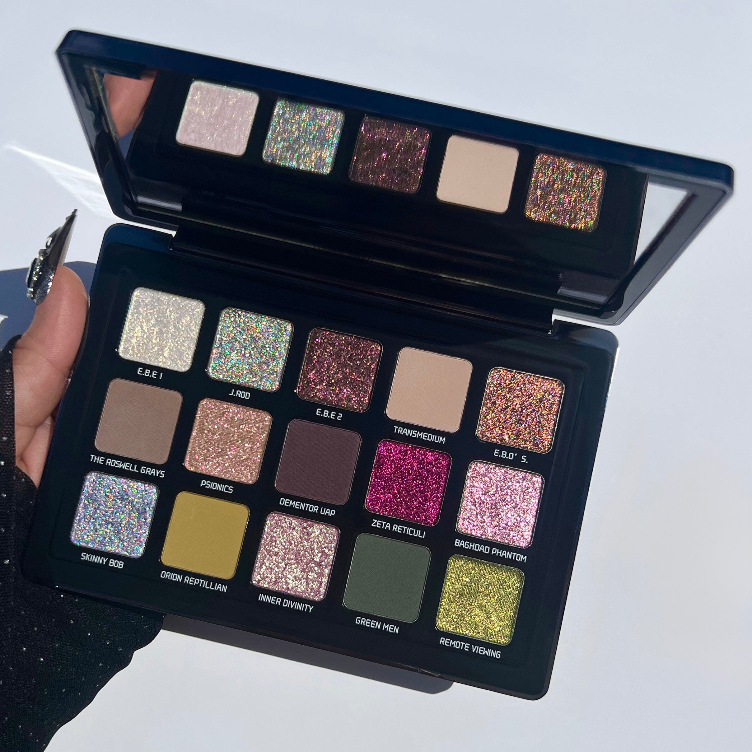 Makeup palette with various colors and a mirror on a light gray background