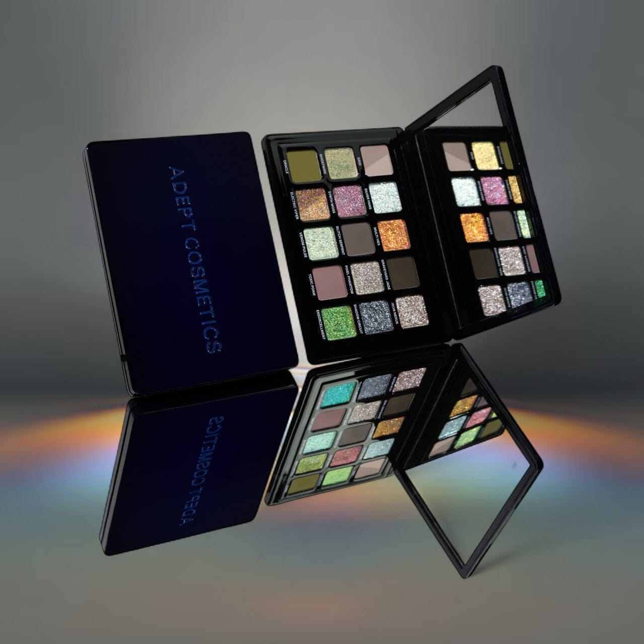 Makeup palette with Adept Cosmetics branding on a reflective surface.