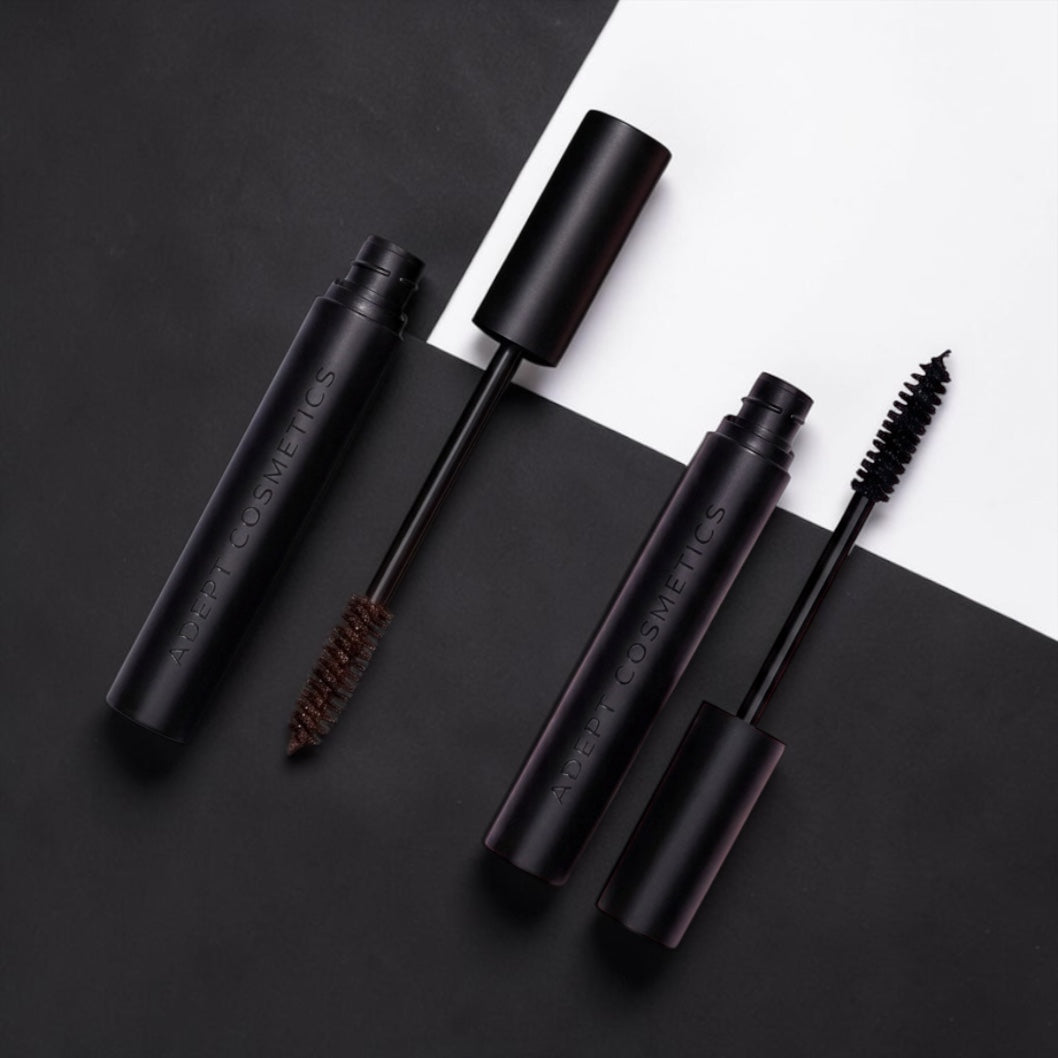 Two black mascara tubes with brushes on a black and white background