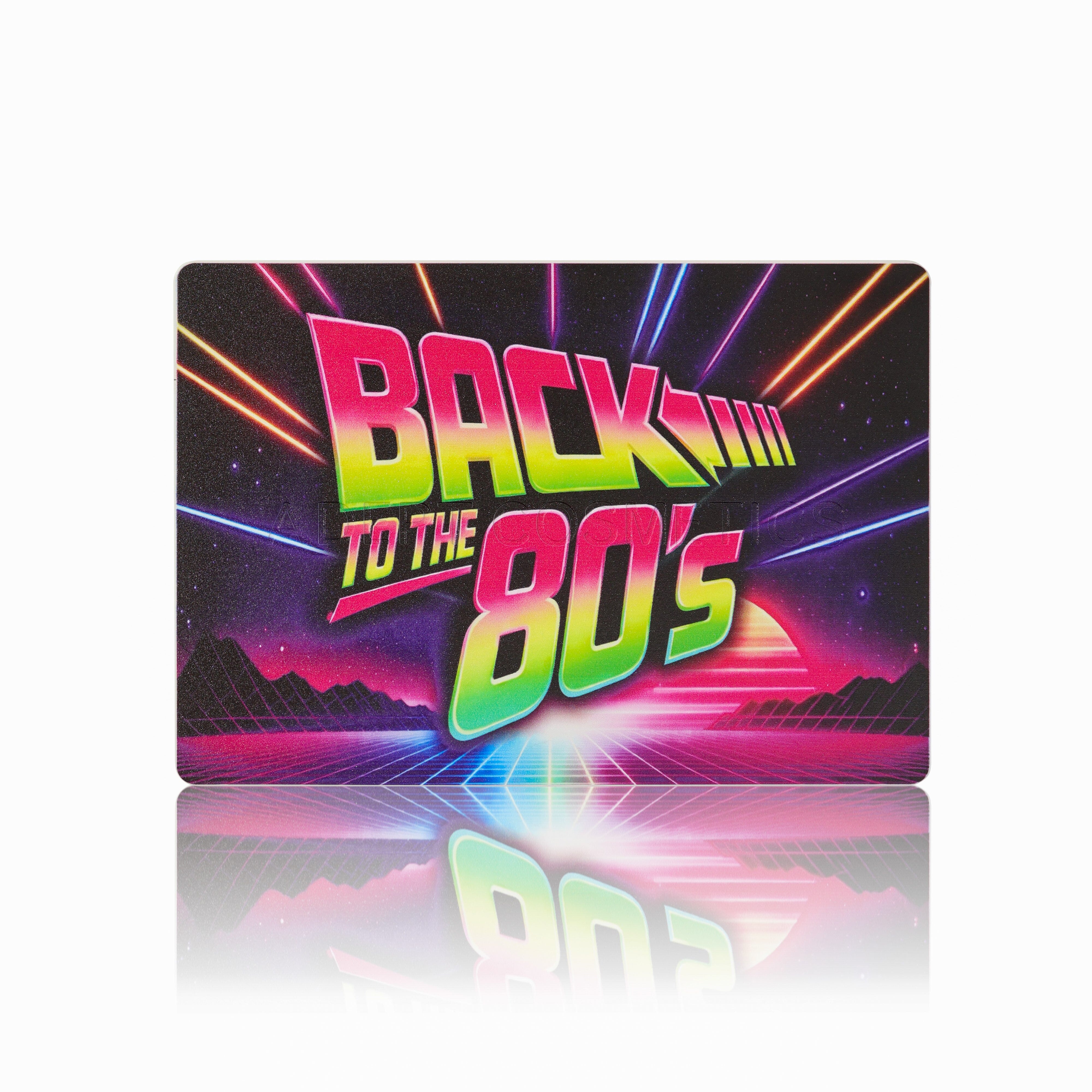 A rectangular mousepad featuring a retro 1980s synthwave design with the text 'BACK TO THE 80's' in neon green, pink, and yellow gradient lettering, set against a black background with colorful light rays and a grid pattern. The mousepad is displayed on a clean white surface with a soft reflection underneath.