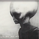 Black and white image of an alien figure with a large head and small body.