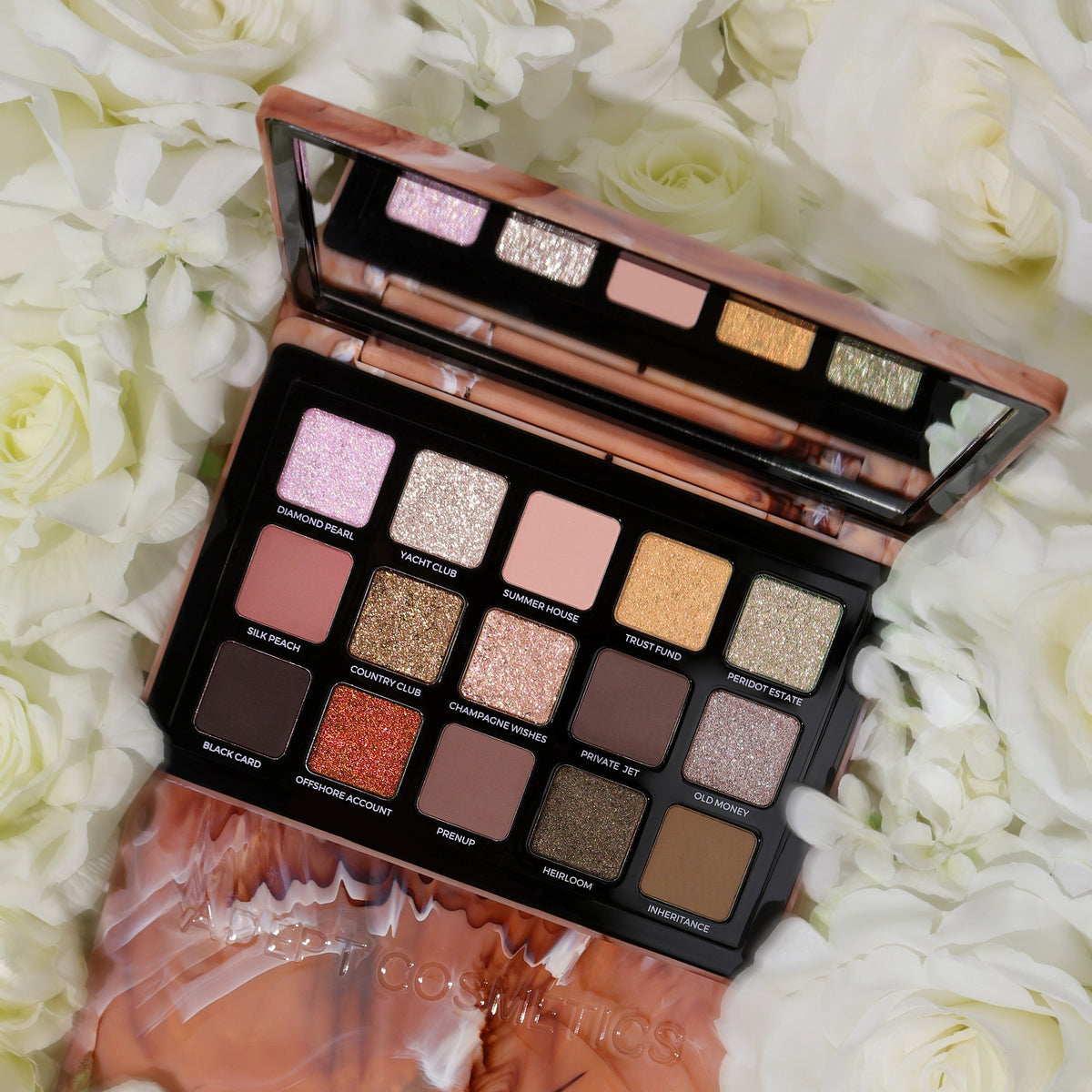 Adept Cosmetics 15-Shade Eyeshadow Palette in a rose gold marble finish, displayed open on a bed of white roses. The palette contains a variety of matte, shimmer, and glitter shades in pink, gold, brown, and bronze tones.